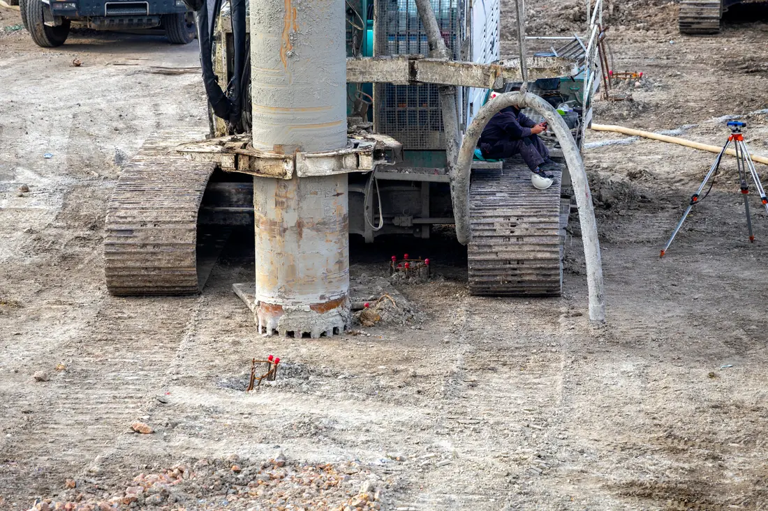 Drill rig on site with survey tripod in the background