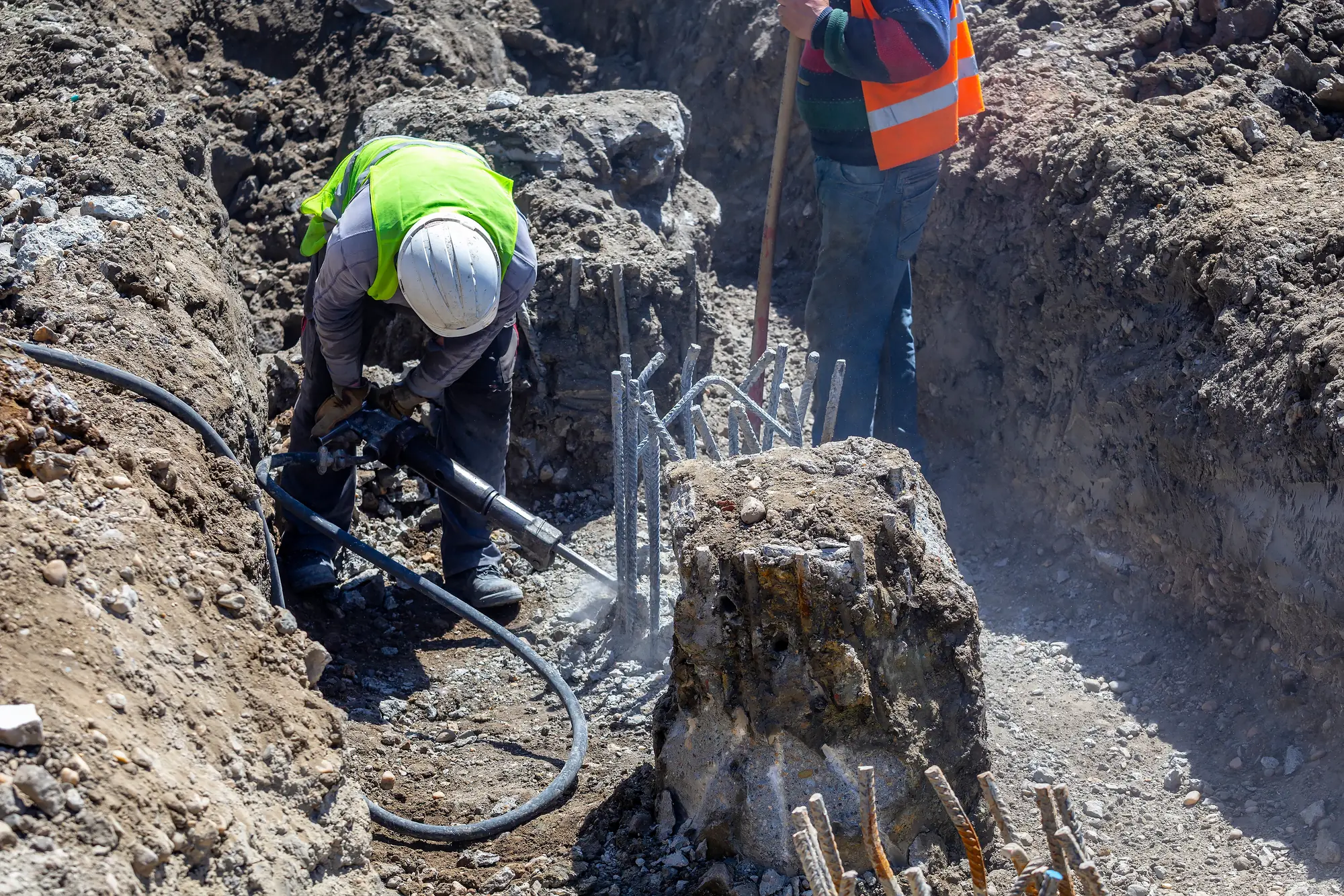 Worker in full PPE operating a jackhammer on site